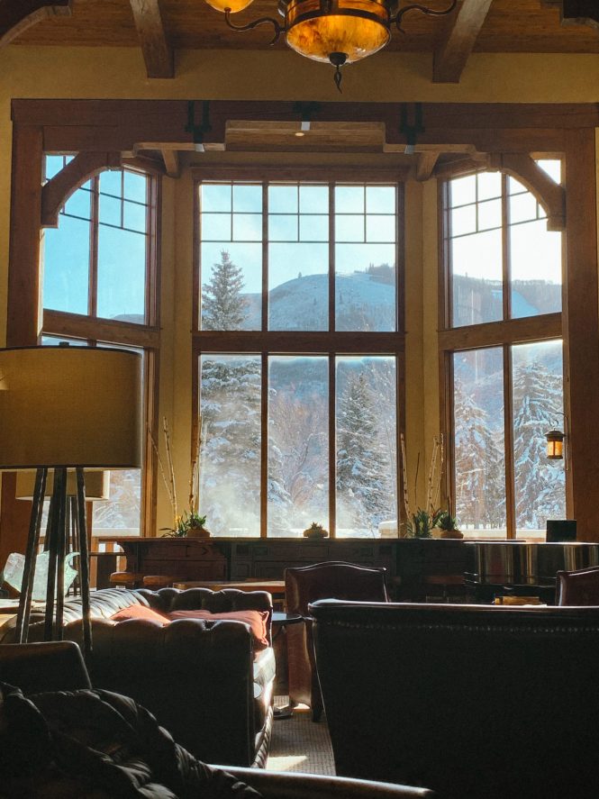Park City Hotel lobby with large windows overlooking a snowy mountain with tall pines