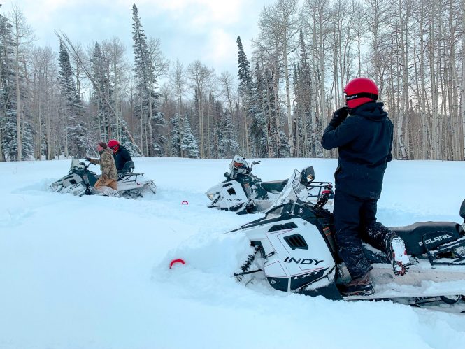 men getting stuck in the snow in snowmobiles