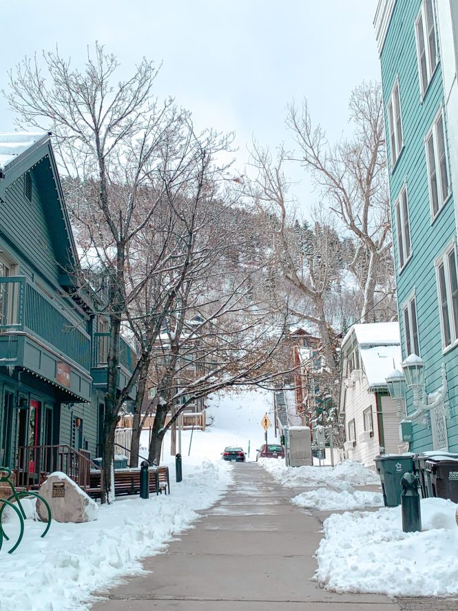 downtown alley in park city, utah with blue buildings and snow along the sidewalk